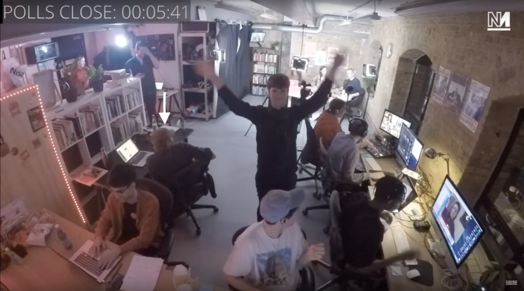 Group of people in event space with one person's arms raised, "Polls Close" countdown timer visible