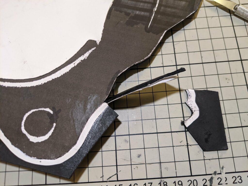 Dark fabric puppet with white curved stripes and C marking, cables above, numbered chart visible on tiled background