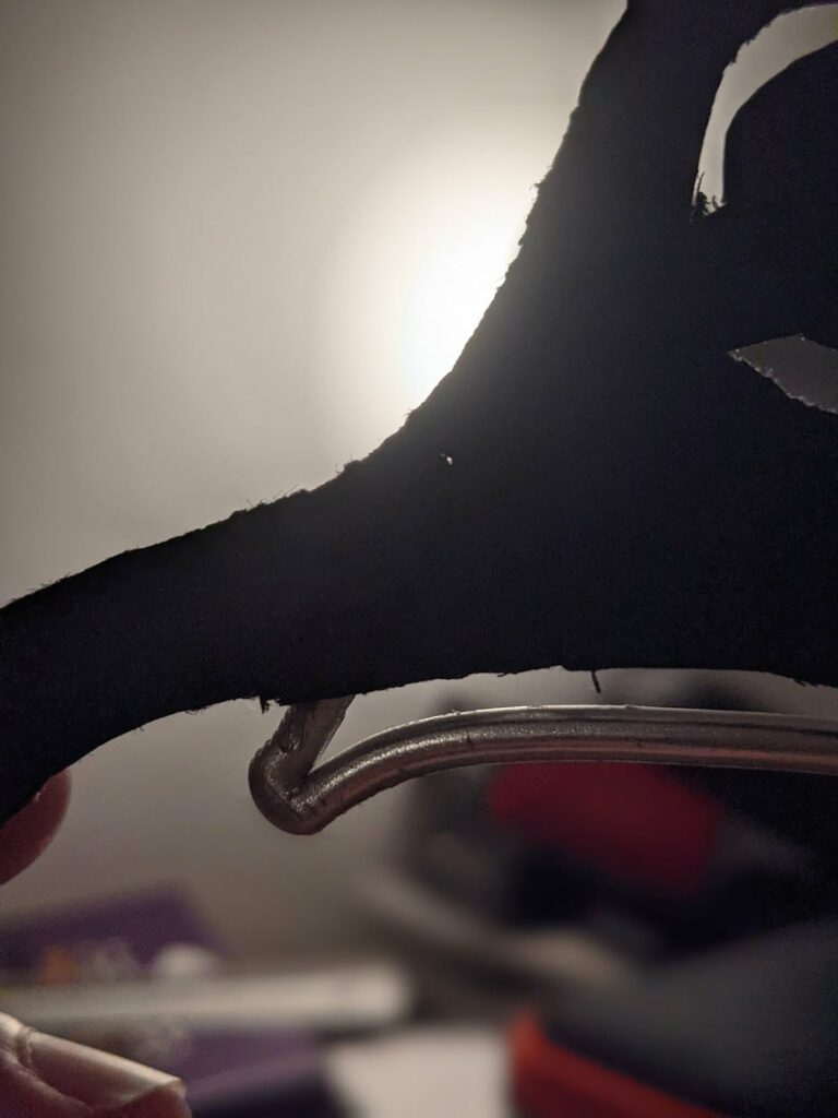 Curved dark fabric shape of puppet with metal rod armature visible against light background