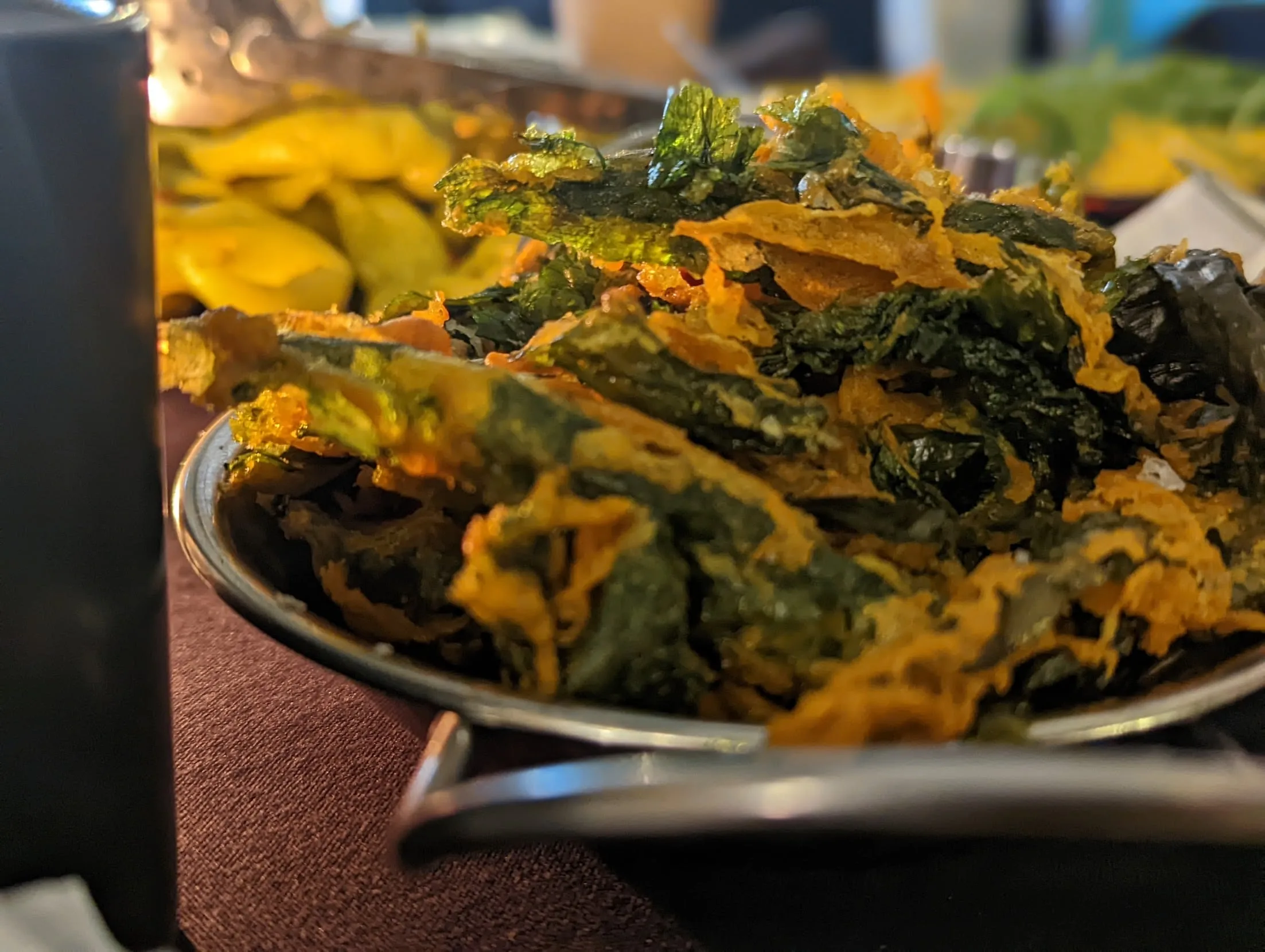 Crispy fried kale chips in metal bowl