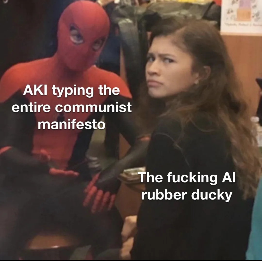 Meme of Spider-Man explaining something intensely to a skeptical MJ. Text over Spider-Man reads: AKI typing the entire communist manifesto. Text over MJ reads: The fucking AI rubber ducky.