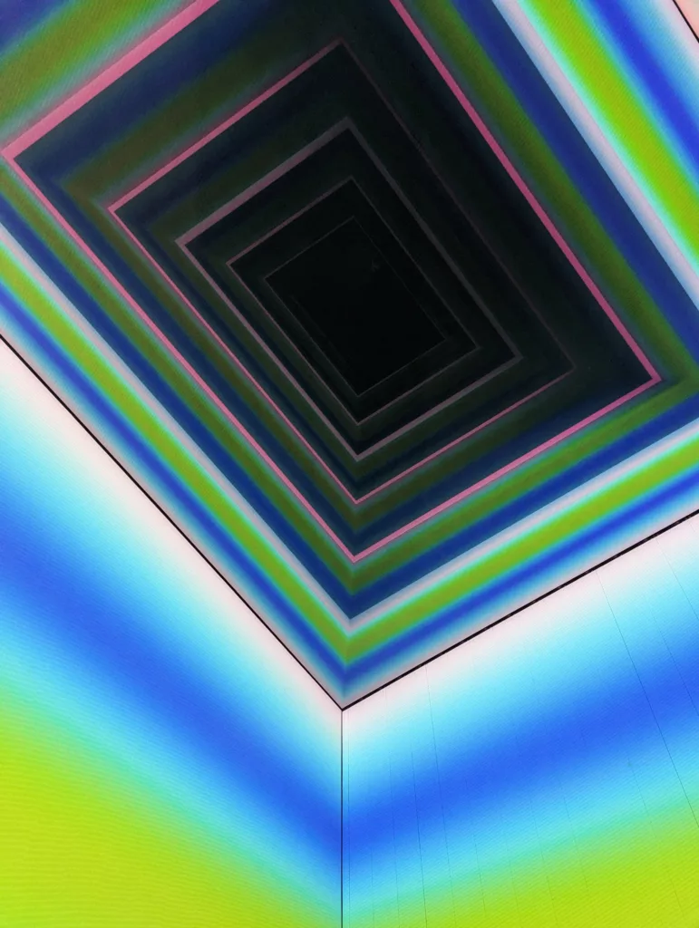 Receding neon rectangles of pink, green, and blue creating a dark tunnel effect above a corner with soft blue and lime light gradients.