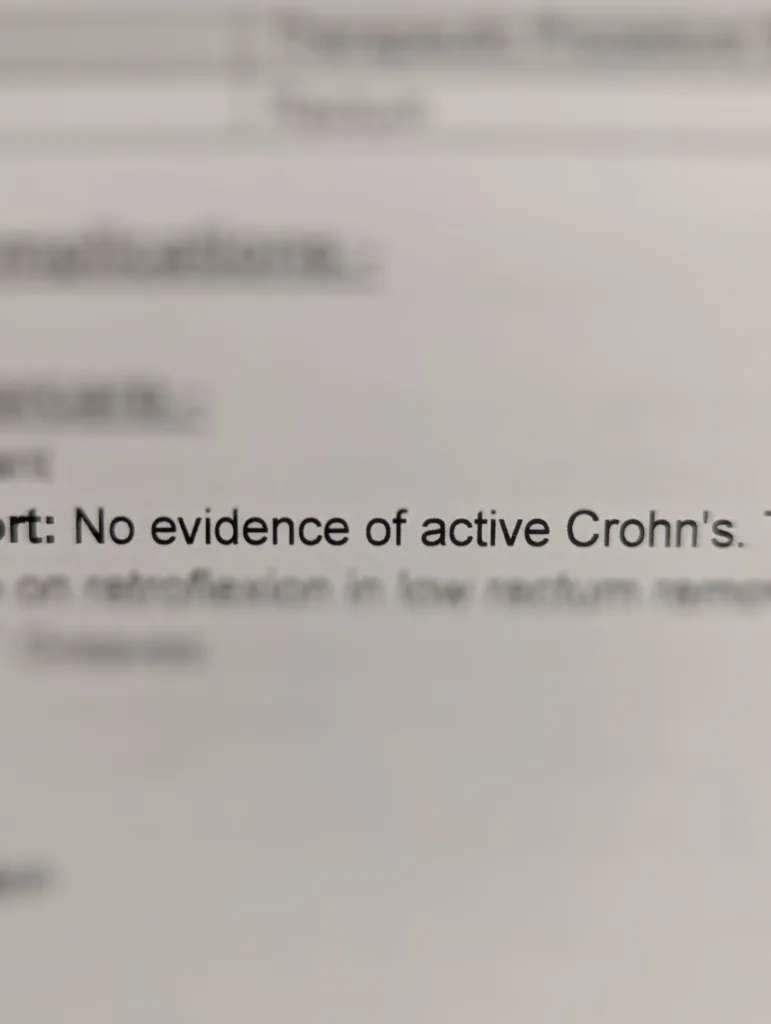 Close-up of a medical report where the line No evidence of active Crohn's is in sharp focus while the rest of the text is blurred.