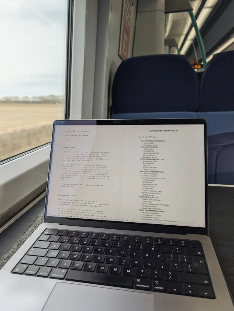 A laptop open on a train table shows a draft titled Slop Machines of Loving Grace, with blue seats and a landscape visible through the window.
